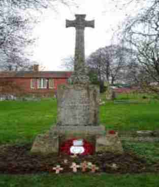 Celtic cross gravestone surrounded by flowers and decorative elements in a serene cemetery setting.