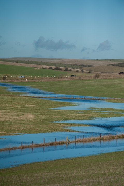 Scenic view of a winding river flowing through lush green fields under a clear blue sky, showcasing the tranquility of the natural landscape.