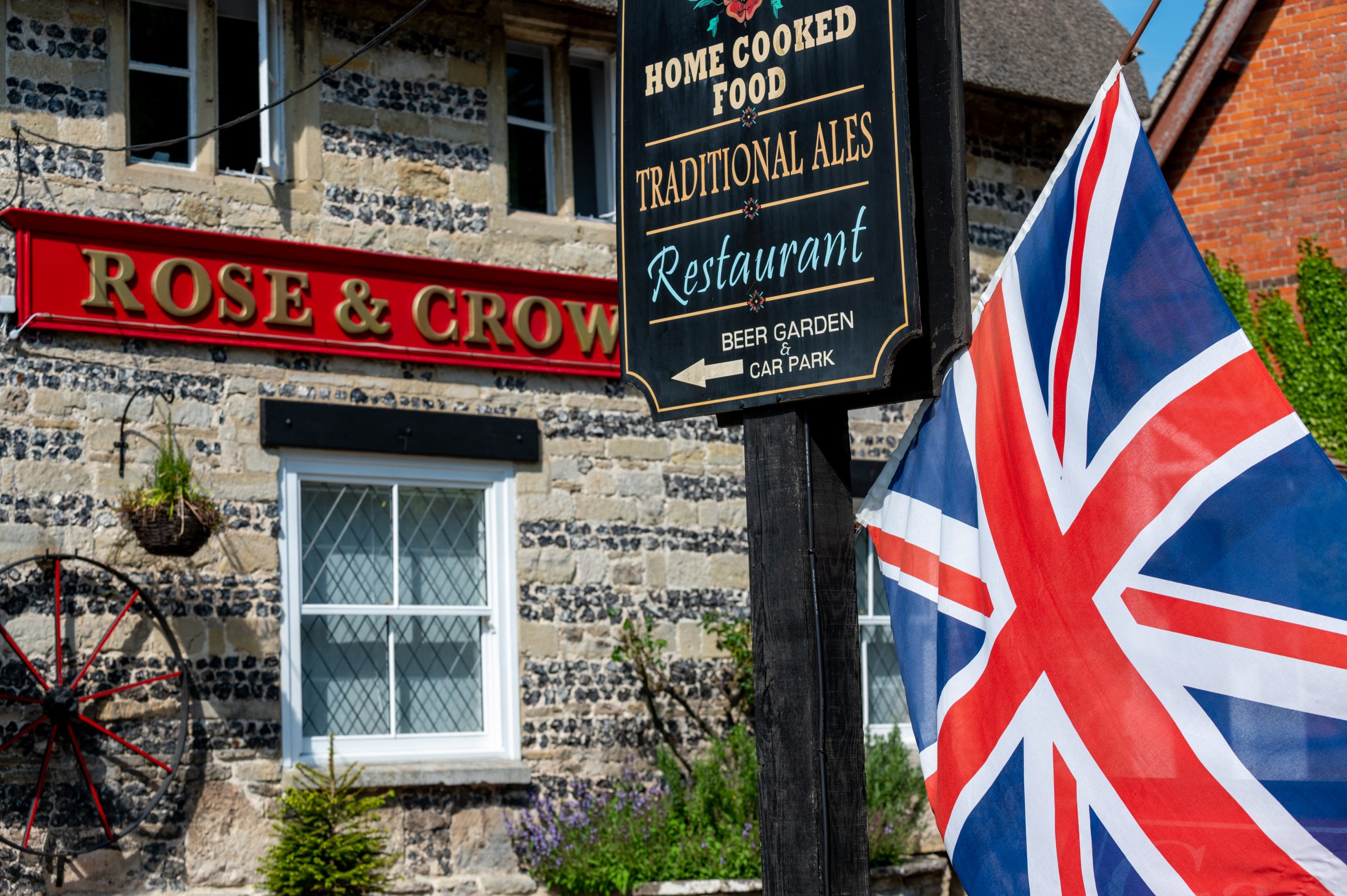 Exterior view of the Rose & Crown pub featuring a traditional British flag, showcasing its historic charm and inviting atmosphere.