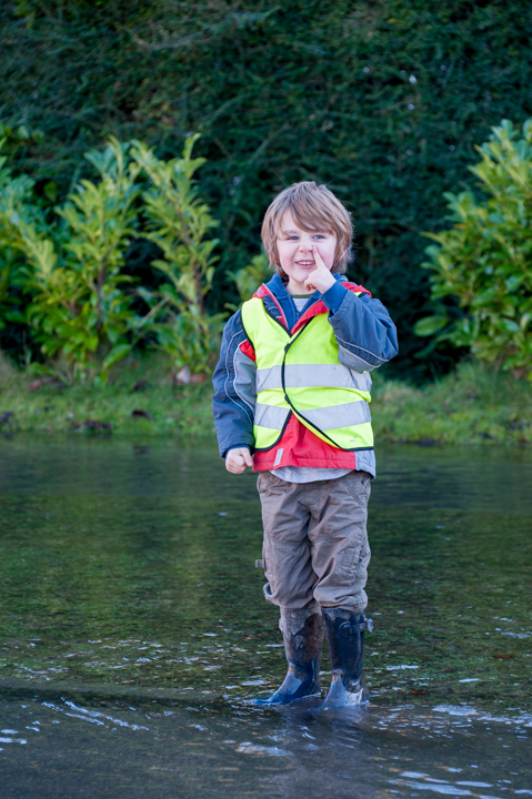 small boy paddling in flooded road